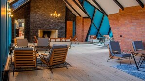A spacious lounge area with wooden flooring, modern furniture, and a brick wall.