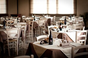 Un restaurant doté de nombreuses tables, chacune étant mise avec des verres à vin, des bouteilles et des couverts.