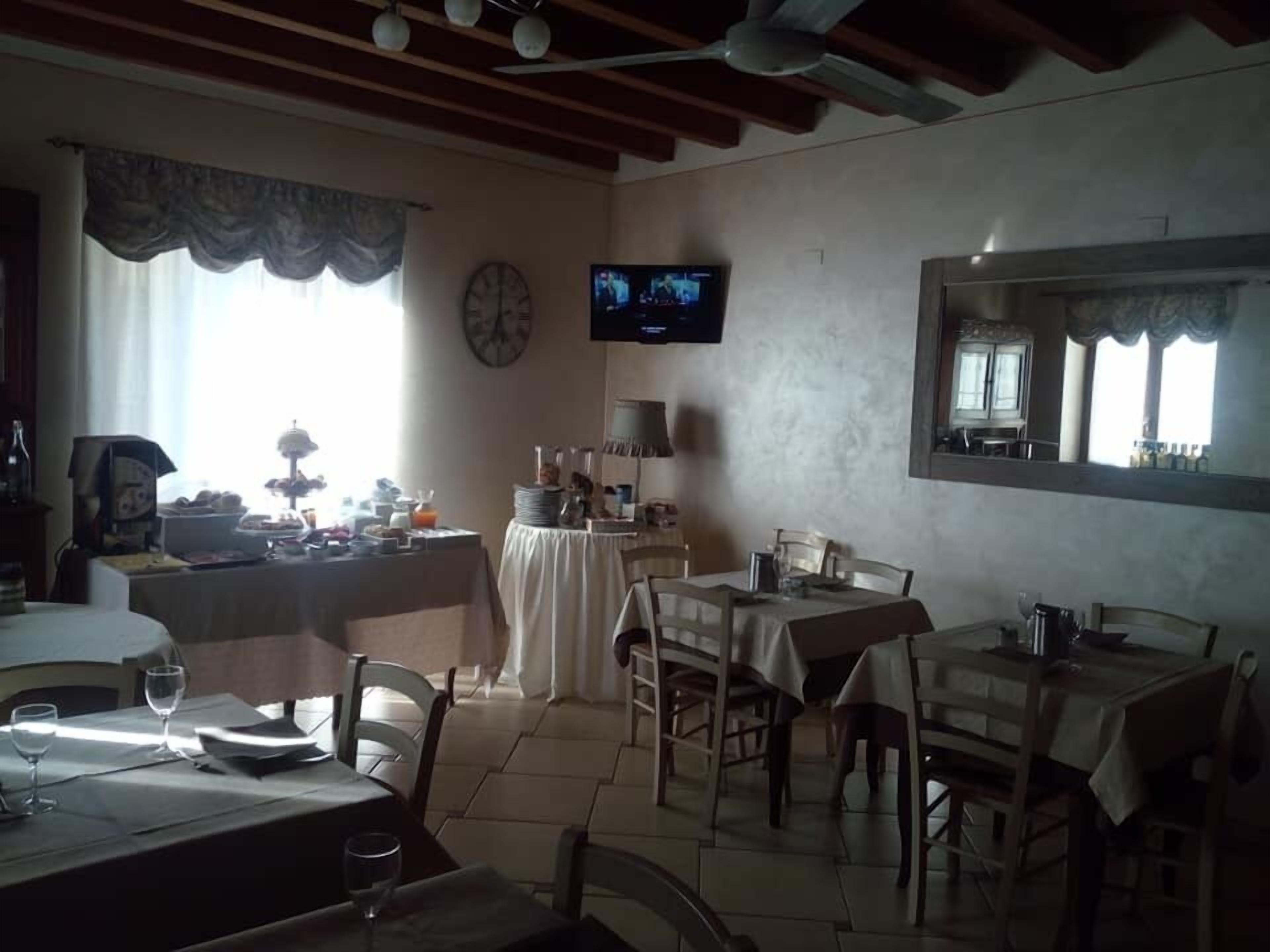 Un espace repas avec des tables et des chaises, un téléviseur fixé au mur et une horloge au mur.