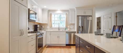 A modern kitchen with white cabinets, stainless steel appliances, and a large island with drawers.