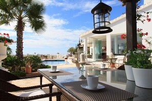 A poolside area with a glass table, wicker chairs, and a hanging lantern. - Villa Azalea - Exclusive villa with unique mediterranean view (Mijas Costa)