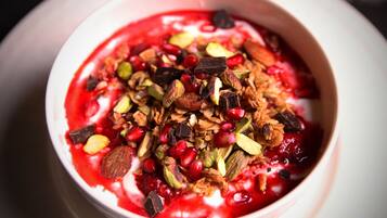 Un tazón de yogur cubierto de granola, semillas de granada y nueces.