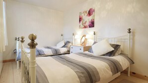 A bedroom with two single beds, a nightstand with a lamp, and a wall-mounted artwork.