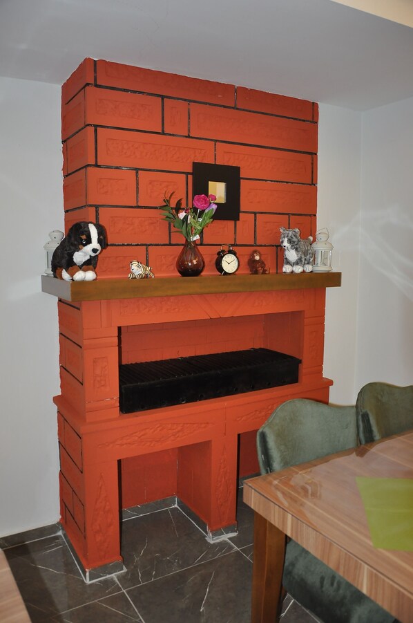 A brick fireplace with a shelf above it holding a vase, a clock, and a cat figurine.