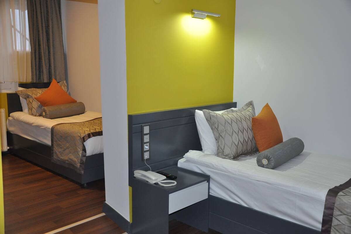 Une chambre d’hôtel avec deux lits, chacun étant équipé d’une table de chevet, d’une lampe et d’un téléphone.