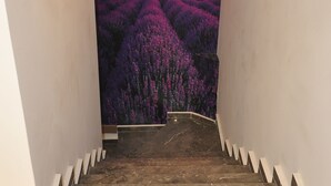 Una escalera con un mural de un árbol contra un atardecer y flores moradas.