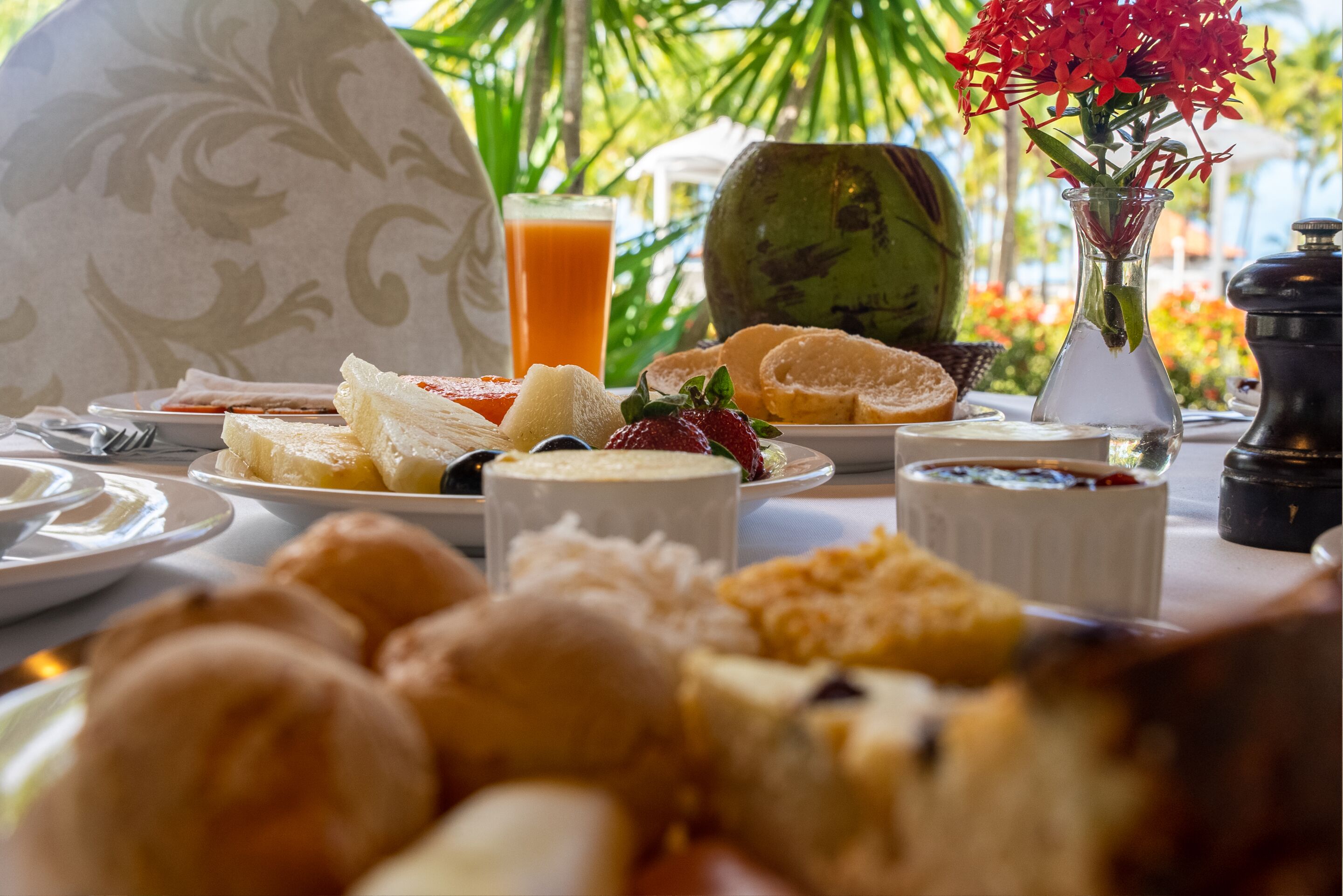 Una mesa con alimentos para el desayuno, como pan, frutas y un vaso de jugo de naranja.