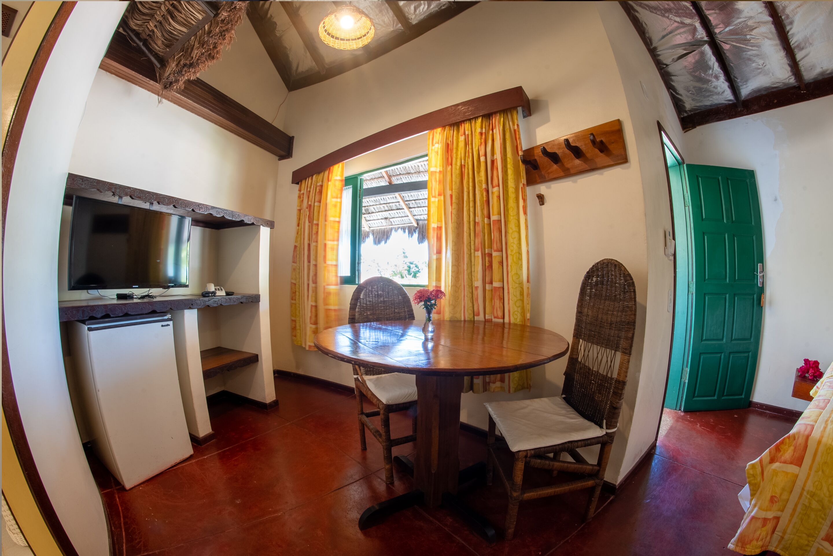 A compact kitchen with a refrigerator, a dining table with chairs, and a green door.