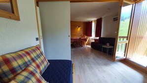 Une pièce comprenant un lit, un canapé, un coin repas et une porte-fenêtre coulissante donnant sur un espace extérieur.