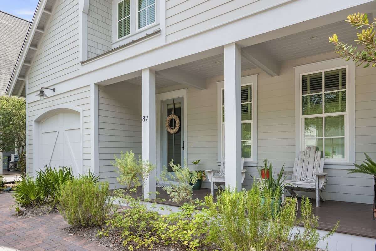 A two-story house with a covered porch, a front door with a wreath, and a number '87' on the door.