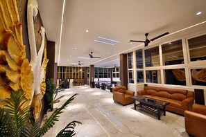 Eine großzügige Lobby mit Marmorboden, Ledersofas und Deckenventilatoren.