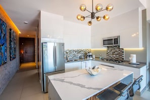 A modern kitchen with a central island, stainless steel appliances, and a unique chandelier.
