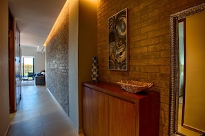 A hallway with a wooden reception desk, a checkered vase, and a large abstract painting on the wall.