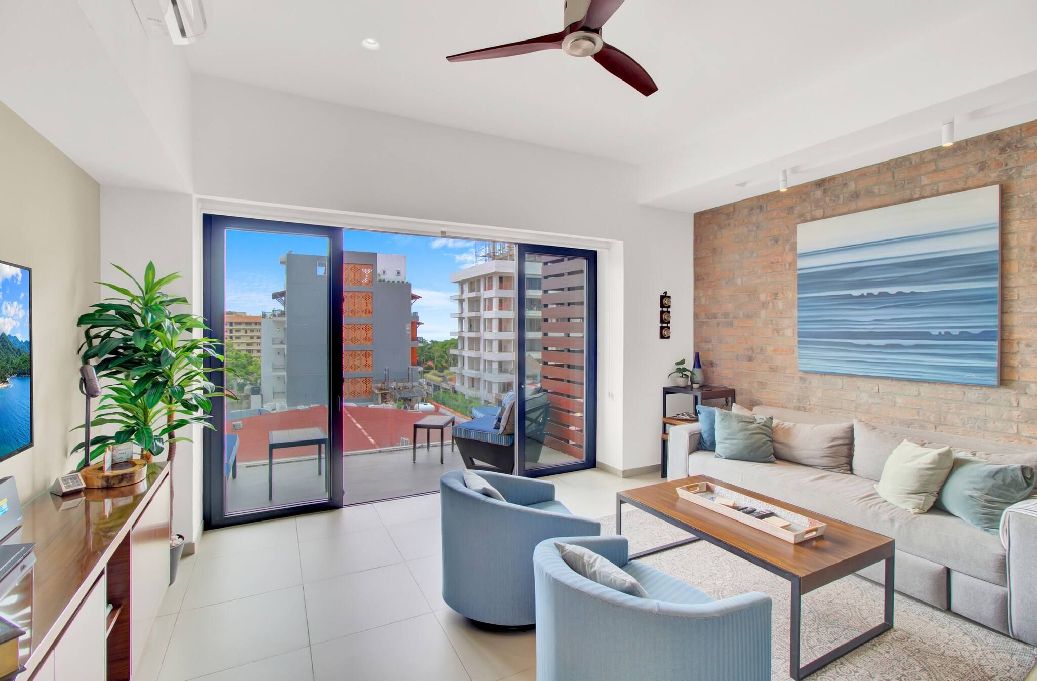 A modern living room with a balcony, a sofa set, a coffee table, and a view of a cityscape.