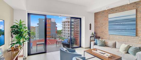 A modern living room with a balcony, a sofa set, a coffee table, and a view of a cityscape.