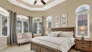 A bedroom with a large bed, a sofa, and a nightstand. - A Rare Find! Lely Resort Single Family Home in Prestigious Majors Community (Naples)