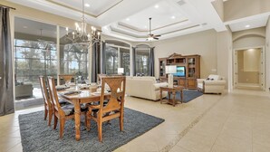 A spacious living room with a dining area, large windows, and a ceiling fan. - A Rare Find! Lely Resort Single Family Home in Prestigious Majors Community (Naples)