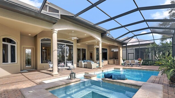 A covered outdoor swimming pool with lounge chairs and a patio area. - A Rare Find! Lely Resort Single Family Home in Prestigious Majors Community (Naples)