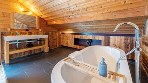 A wooden cabin interior with a large bathtub, wooden shelves, and a mirror. - Chalet-Sixtine (Le Grand-Bornand)