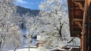 A wooden bridge with snow-covered railings leading to a building with a wooden facade. - Chalet-Sixtine (Le Grand-Bornand)