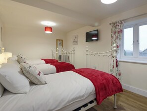 A bedroom with two beds, a television, a window with curtains, and a ceiling light. - Harbour View - UKC2303 (Wainfleet St. Mary, near Skegness)