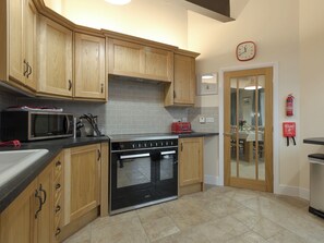 A kitchen with wooden cabinets, a microwave, a toaster, and a stove. - Harbour View - UKC2303 (Wainfleet St. Mary, near Skegness)