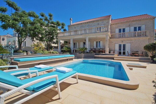 Piscina com espreguiçadeiras e um terraço coberto.