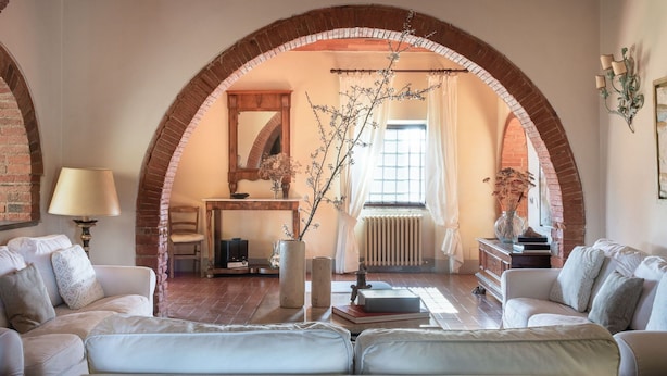 Ein gemütliches Wohnzimmer mit Kamin, gewölbter Ziegeldecke und bequemen Sitzmöglichkeiten.