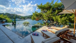 An infinity pool with lounge chairs and a view of a lake and hills. - Luxury Villa Silent with Infinity Pool (Selca)