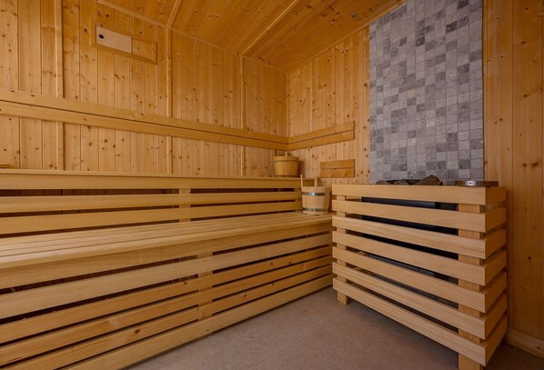 A sauna with wooden benches and a tiled wall.