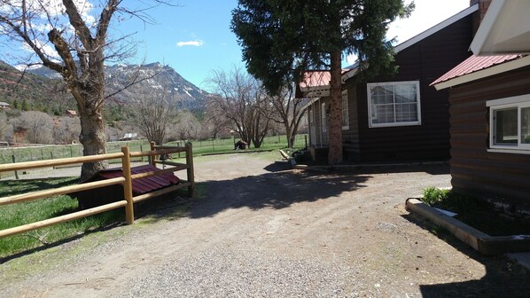 A rustic cabin with a gravel driveway, wooden fence, and a bench. - Large cabin in Ouray County, easy access, lots of room to roam STR-1-2024-017 (Ridgway)