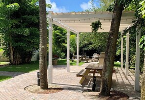 Un espacio al aire libre techado con mesas de picnic y una pérgola.