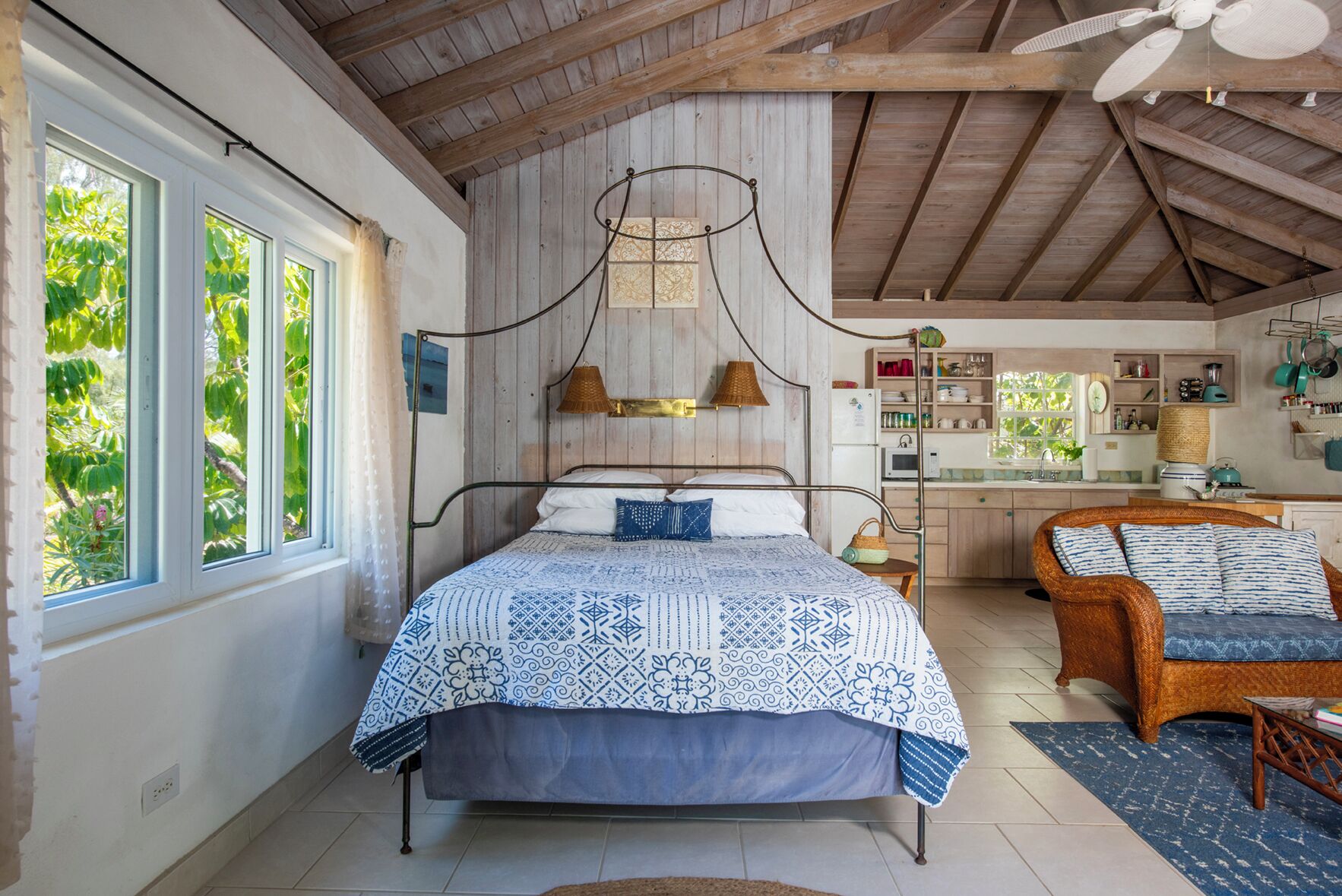 Een slaapkamer met een bed, een stoel, een bureau en een keukenhoek.