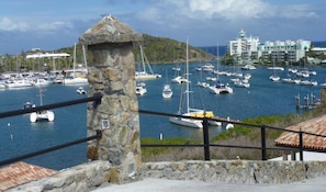 A marina with multiple boats, a stone structure, and a building with balconies in the background. - Newly Renovated Luxurious Ocean View Condo  (French Cul de Sac)