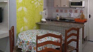 A compact kitchen with a microwave, a sink, and a small dining area with a table and chairs. - PRAIA GRANDE: Comfortable 3-bedroom beach house, well located near the sea. (Praia Grande)