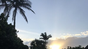 A swimming pool with lounge chairs and palm trees, with the sun setting in the background. - Beachfront Gulf View Condo w/Lanai, Pool & Easy Access to Beach, Sunset Views 🏖 (Marco Island)