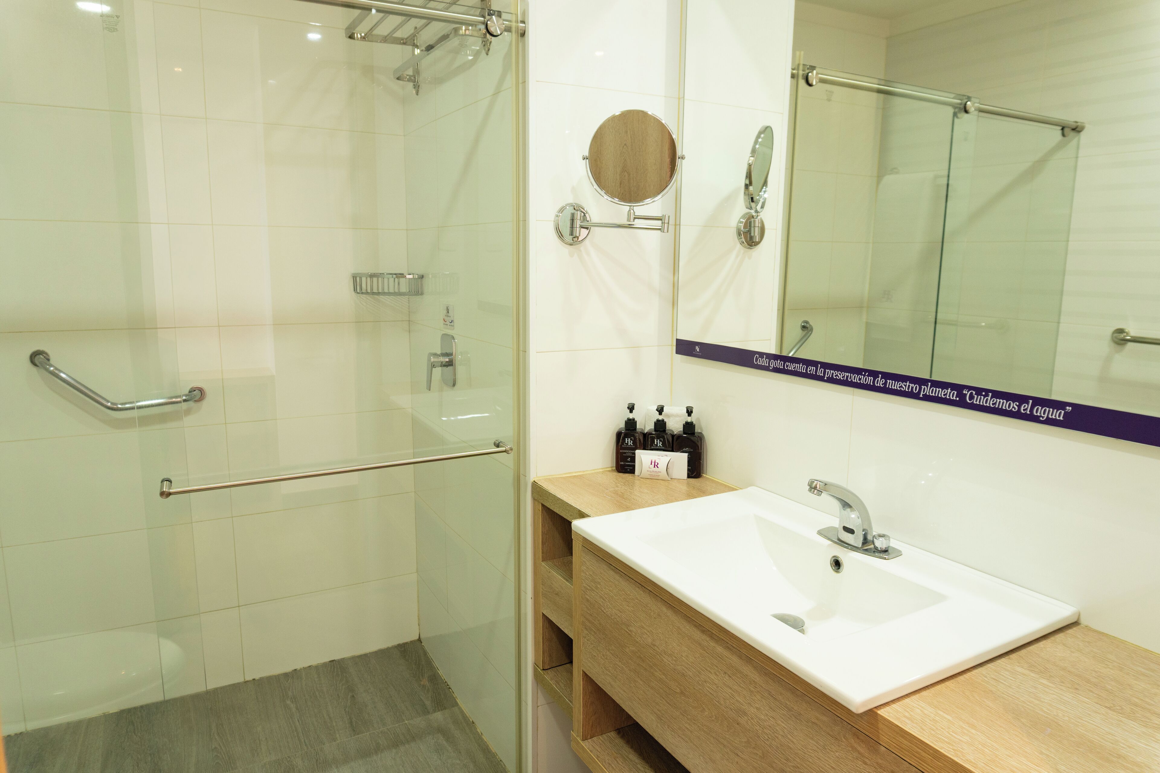A modern bathroom with a glass shower enclosure, a white sink, and a wooden vanity.