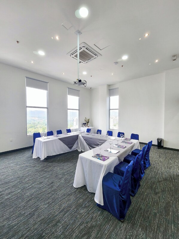 A conference room with a long table, blue chairs, and a projector. - Hotel Roseliere Bucaramanga (Floridablanca)