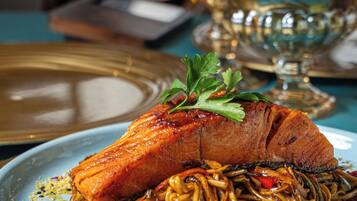 A plate of food with a piece of salmon and noodles.
