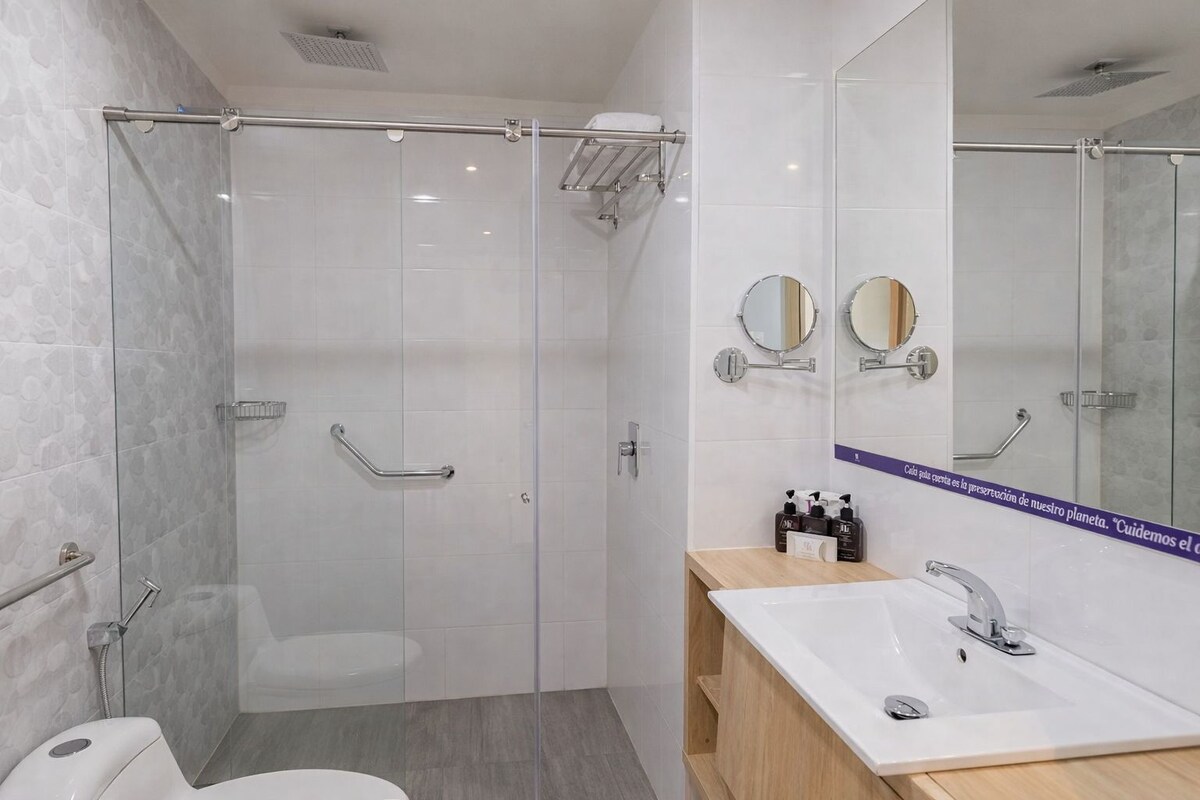 A modern bathroom with a glass shower enclosure, a sink with a vanity, and two wall-mounted mirrors.