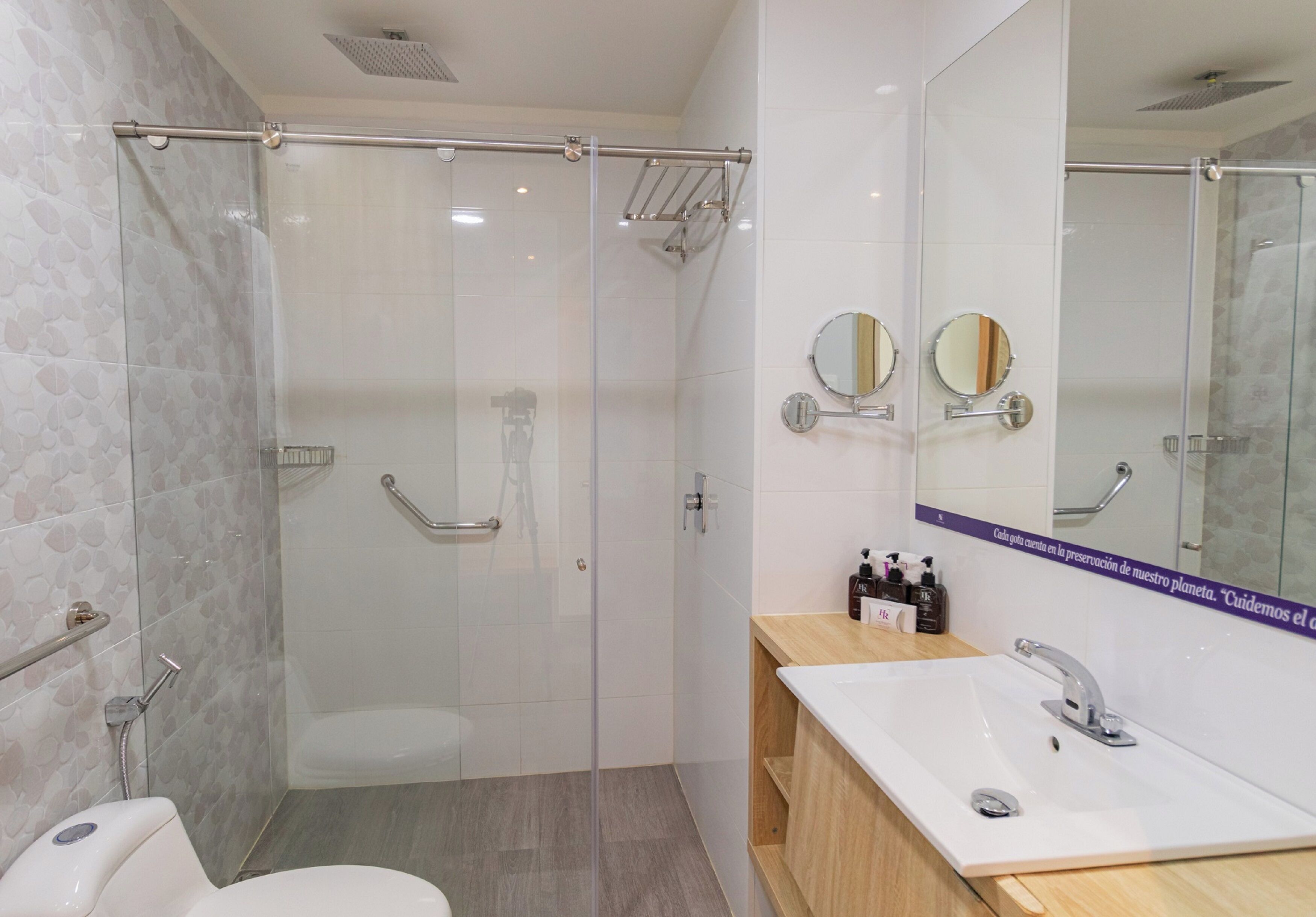A modern bathroom with a glass-enclosed shower, a white sink with a wooden vanity, and two wall-mounted mirrors.