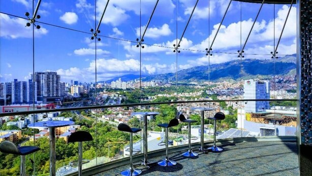 A high-rise balcony with a city view, featuring multiple tables and chairs. - Hotel Roseliere Bucaramanga (Floridablanca)