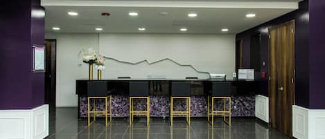 A reception area with a marble counter, black chairs, and purple walls.