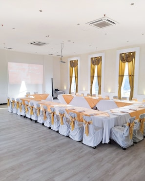 Conference room with a long table and projector screen, ideal for meetings and events.