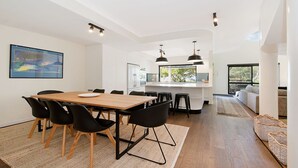 A modern kitchen with a central island, black chairs, and a dining table with a white plate.