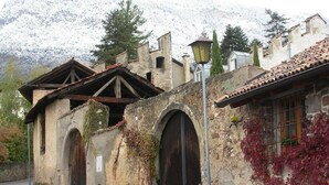 A rustic stone building with arched doorways and ivy-covered walls. - Casa Piganò - living within historic walls (Appiano Sulla Strada del Vino)