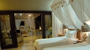 Ein Zimmer mit zwei Betten, einer Sitzecke mit Sofa und Sesseln sowie einer Glastür, die nach draußen führt.