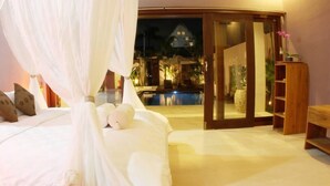 Ein Schlafzimmer mit Himmelsbett, Blick auf einen Pool und einer Glastür zu einem Außenbereich.