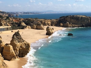 Paisaje costero con formaciones rocosas, una playa arenosa y una vista despejada del mar.