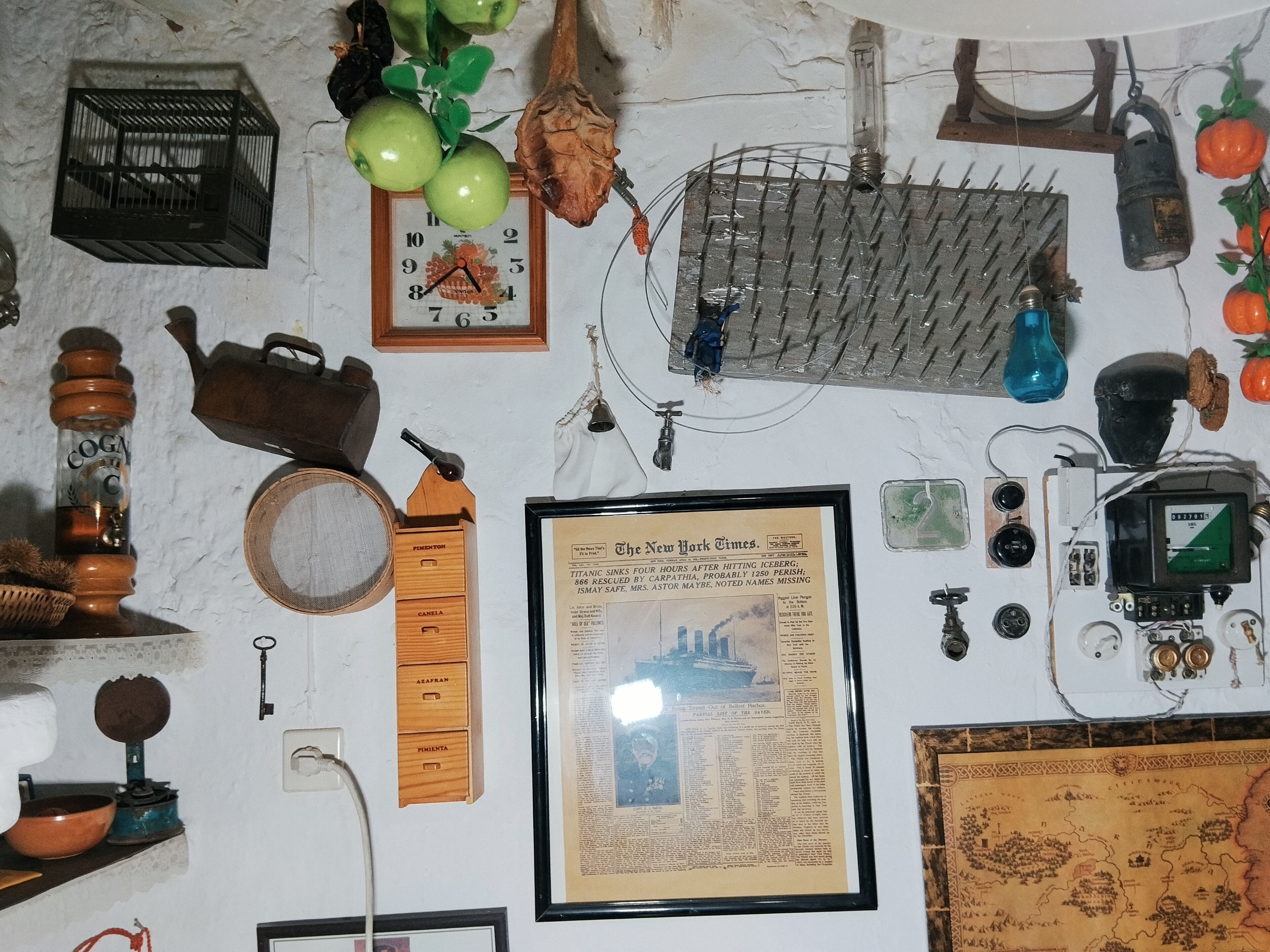 Een muur met diverse historische objecten, waaronder een krantenartikel in een lijst, een klok en een kaart.